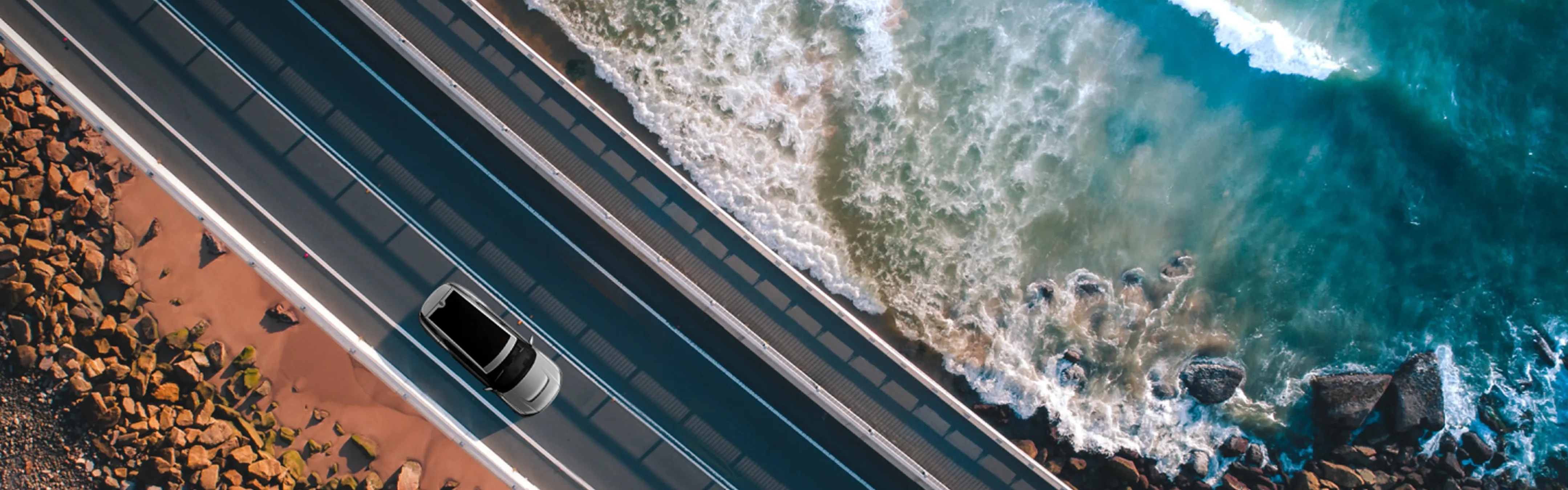Aerial view of a VinFast vehicle driving along a coastal highway